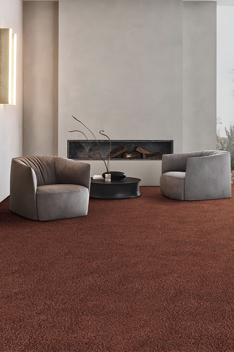 Modern living room with brown carpet, gray chairs, and a fireplace.